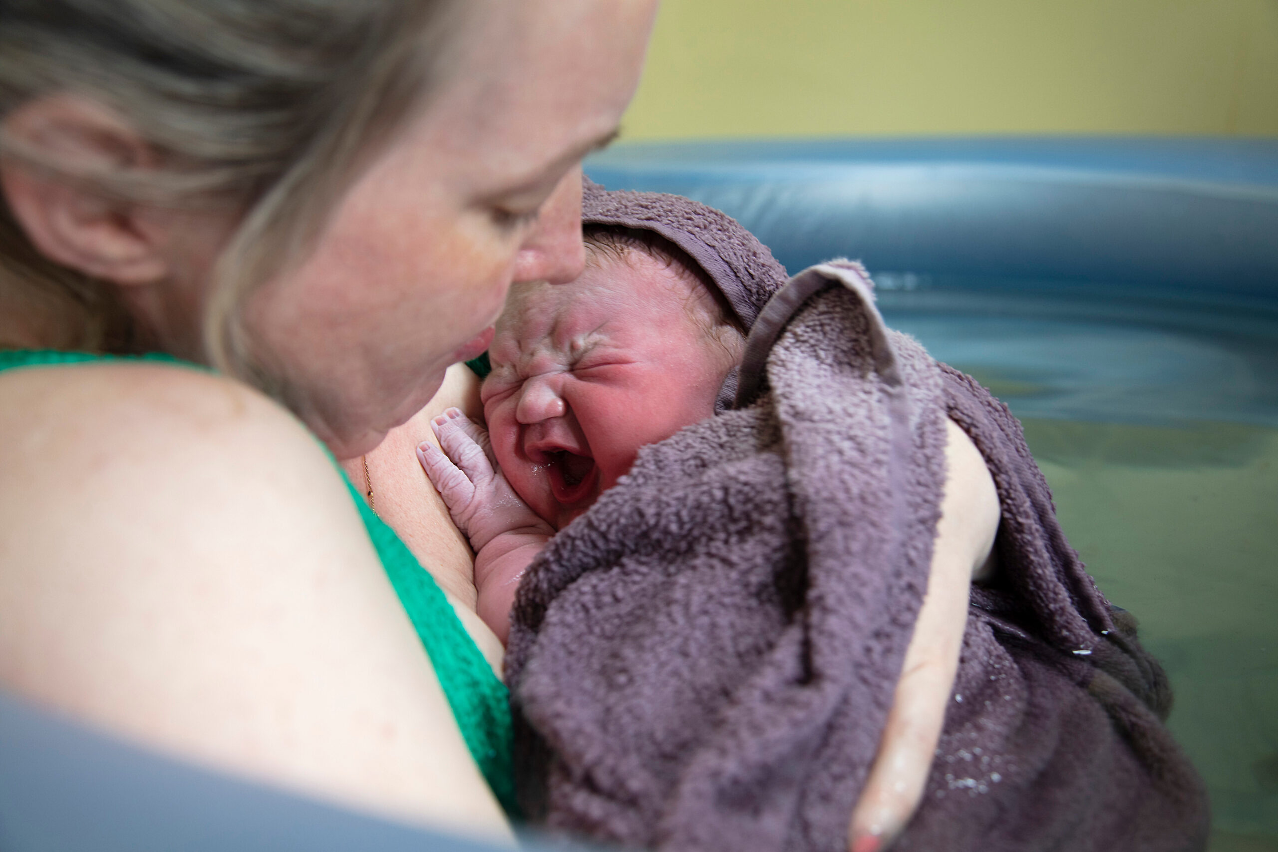 A new mother embracing her newborn baby after a pool birth