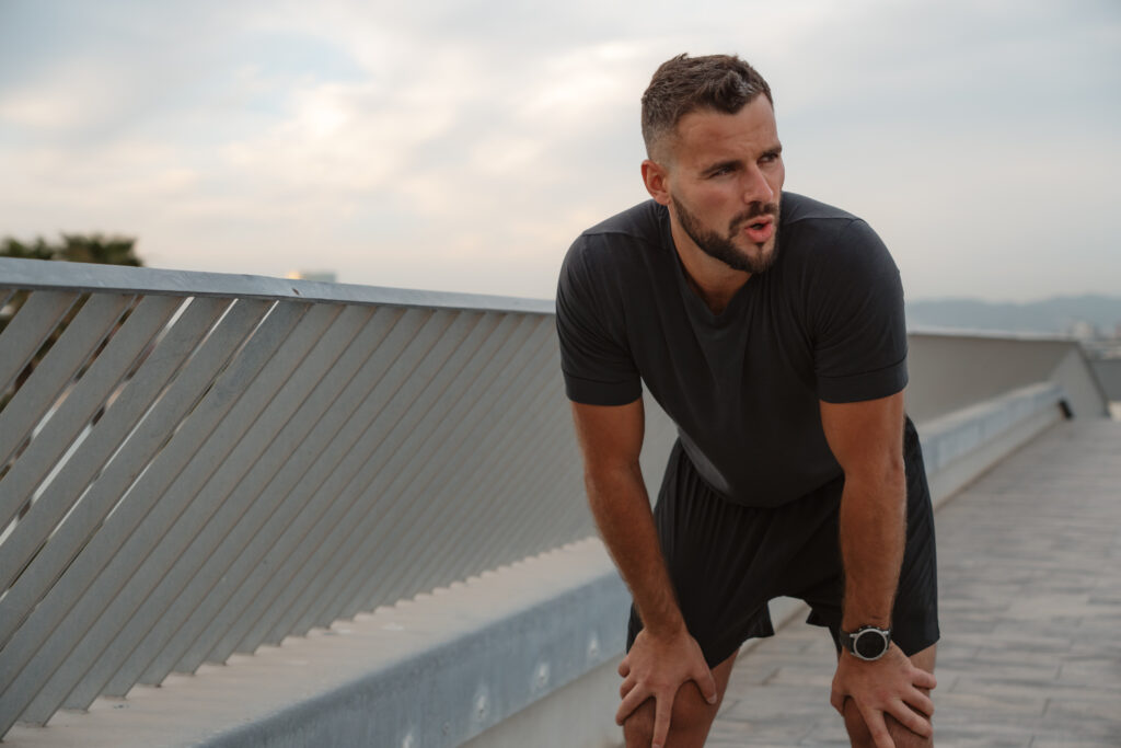 Tired sportsman resting after running on bridge