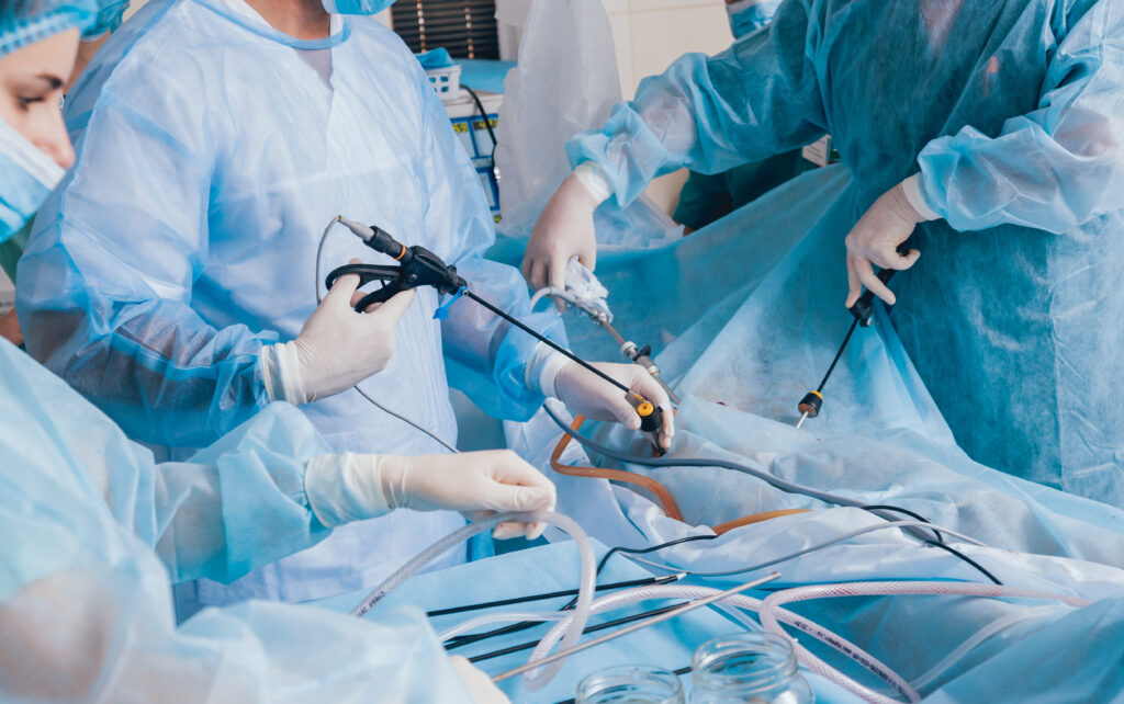 Process of gynecological surgery operation using laparoscopic equipment. Group of surgeons in operating room with surgery equipment. Background