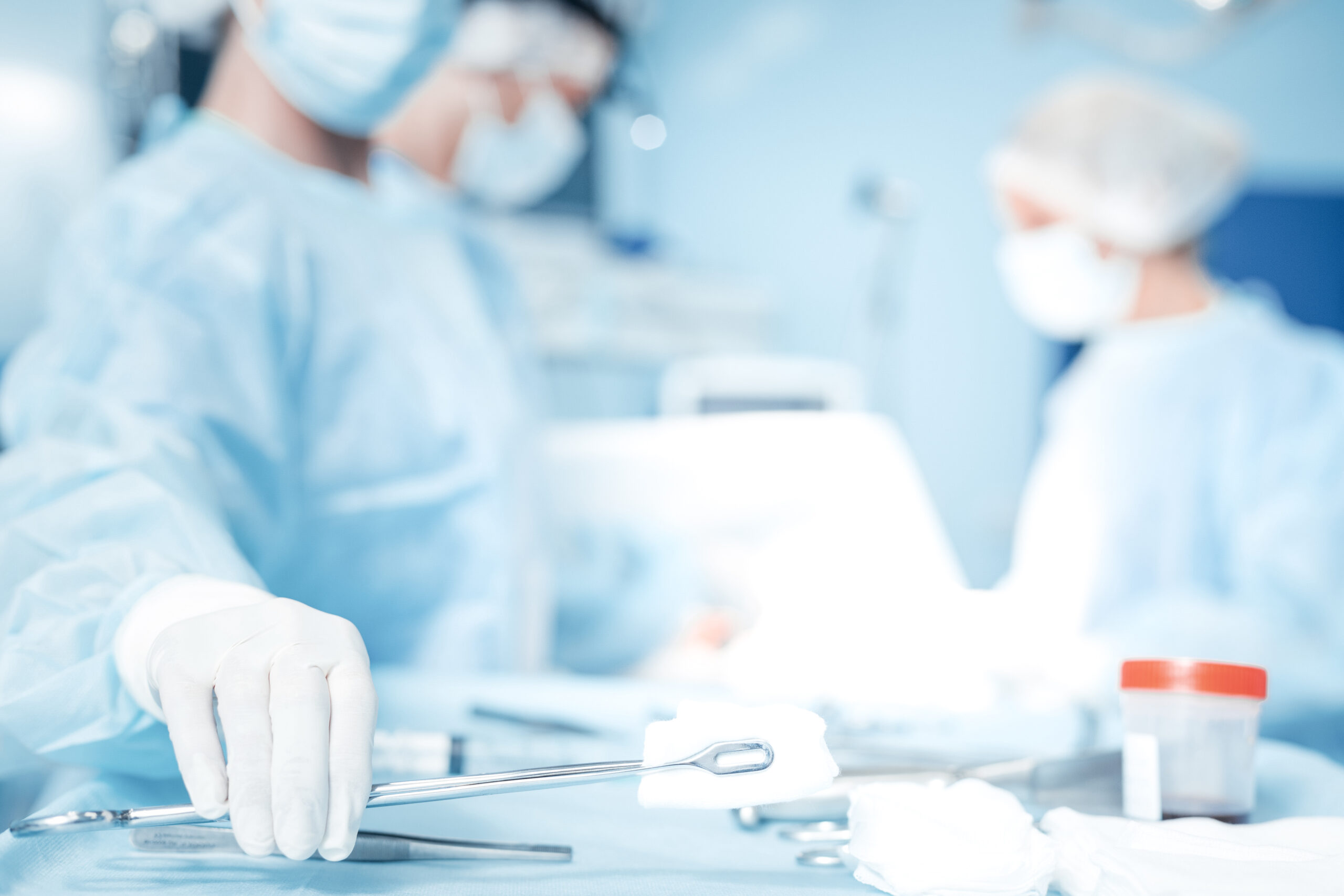 Professional surgery. Selective focus of a surgical instrument being taken by a nice smart professional surgeon during the operation