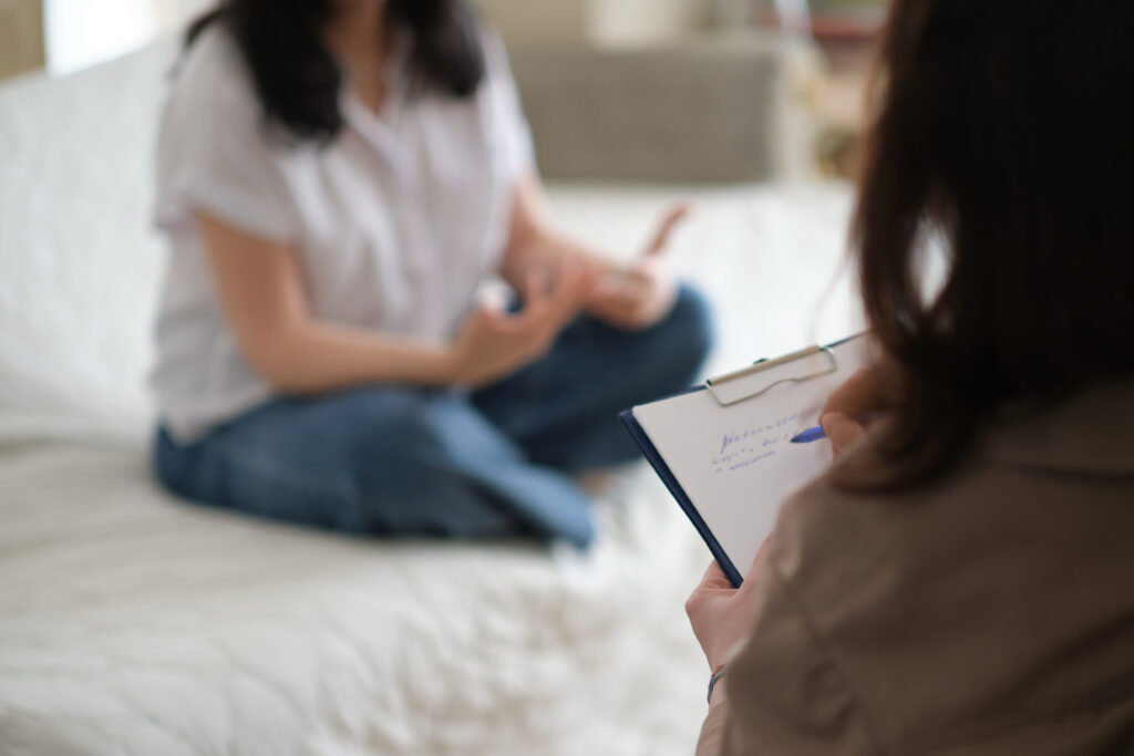 patient makes progress towards healing and recovery as she talks with her therapist about her struggles. psychologist takes notes during the therapy session to help her patient.