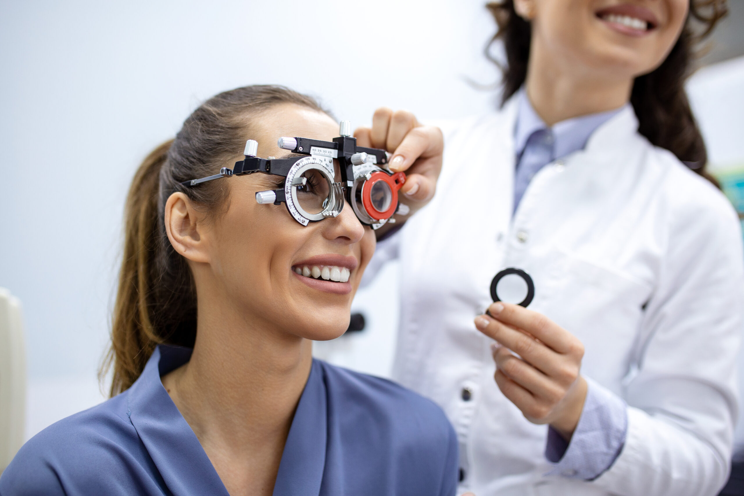 Ophthalmologist examining woman with optometrist trial frame. female patient to check vision in ophthalmological clinic.